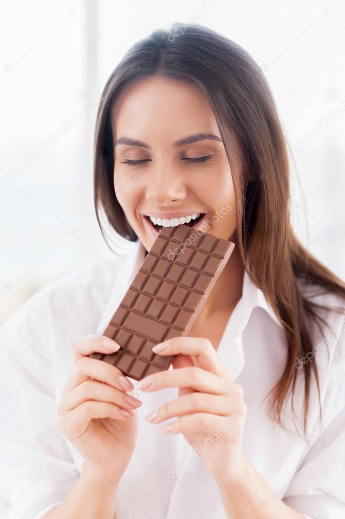Woman in white shirt eating chocolate