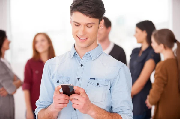 Muž drží mobilní telefon a s úsměvem — Stock fotografie