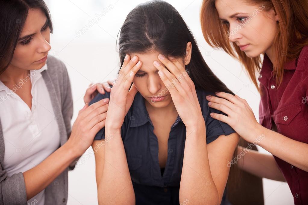 Deprimida mujer sentada en la silla mientras otras dos mujeres consolando — Foto de Stock  