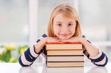 küçük kız kitap yığını eğilerek