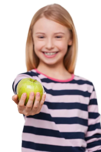 Dela äpple med dig. glad liten flicka sträcker ut handen med grönt äpple stående isolerad på vit — Stockfoto