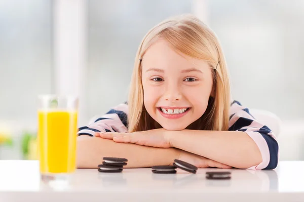 Menina encostada à mesa com biscoitos — Fotografia de Stock