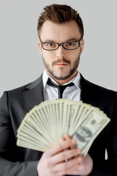 Businessman in glasses holding paper currency and looking at camera — Stock Photo, Image