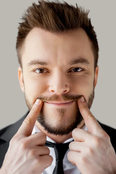 Portrait de jeune homme en tenue de cérémonie faisant sourire par les doigts — Photo