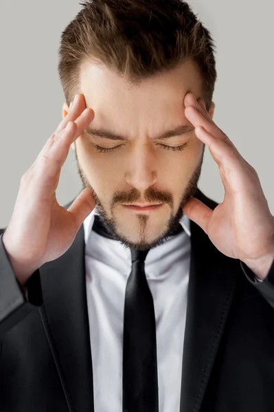 Man in formalwear holding head in hands and keeping eyes closed — Stock Photo, Image