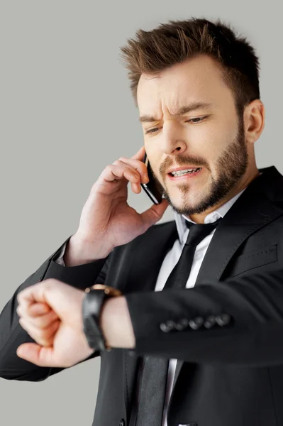 Hombre en ropa formal hablando por teléfono y comprobando la hora — Foto de Stock