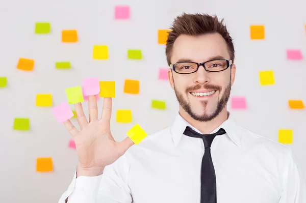 Empresário segurando notas adesivas em seus dedos e sorrindo — Fotografia de Stock