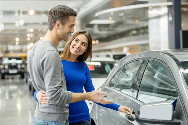 Couple debout chez le concessionnaire en choisissant la voiture à acheter — Photo