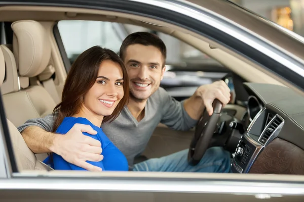 Pareja sentada en el asiento delantero del coche y mirando a cámara — Stock fotografie