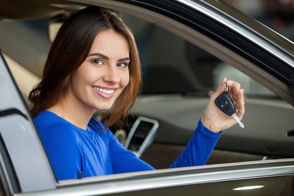 Frau sitzt auf dem Beifahrersitz, hält Schlüssel in der Hand und blickt in Kamera — Stockfoto