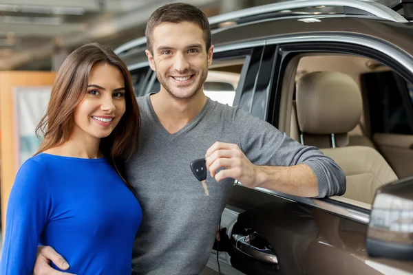 Young men standing near the car, hugging his girlfriend and holding a key — Stock Photo, Image