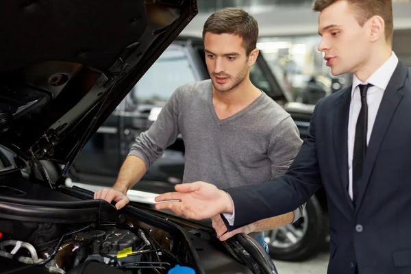 Salesman showing all the car features to the customer — Stock Photo, Image