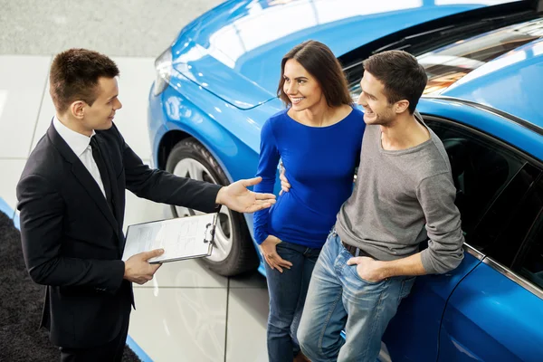 Vendeur de voitures racontant les caractéristiques de la voiture aux clients — Photo