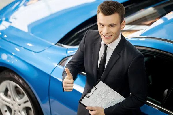 Prodavač auta stojící na obchodní zastoupení drží klíč — Stock fotografie