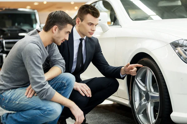 Venditore di auto che mostra i vantaggi della vettura al cliente — Foto Stock