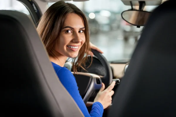 Kobieta siedzi na przednim siedzeniu samochodu, patrząc na kamery — Zdjęcie stockowe
