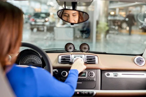 Attraktive junge Frau probiert Neuwagen im Autohaus aus — Stockfoto