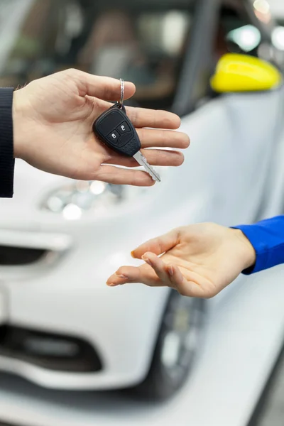 Main de vendeur de voiture donnant la clé au propriétaire féminin — Photo