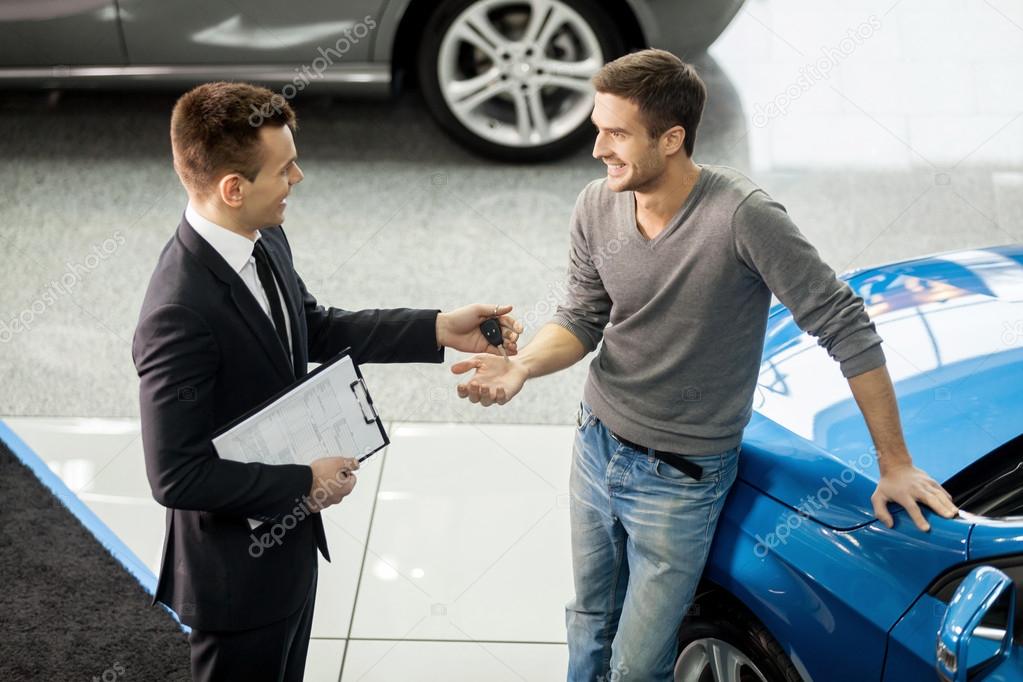 Car salesman making deal with customer at the dealership