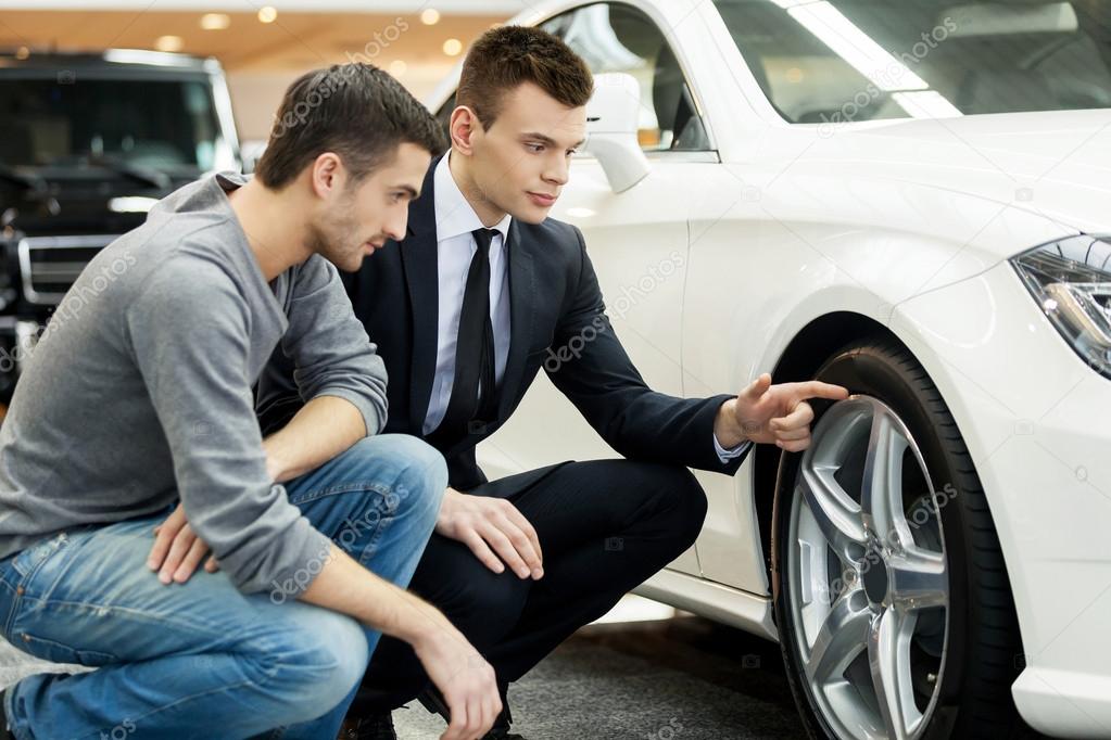 Car salesman showing the advantages of the car to the customer