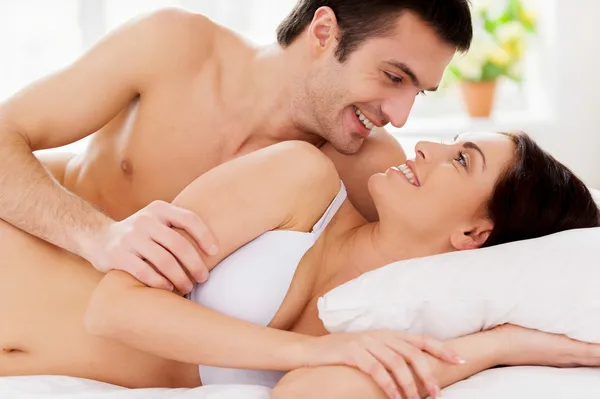 Coppia sdraiata a letto e guardarsi con sorriso — Foto Stock