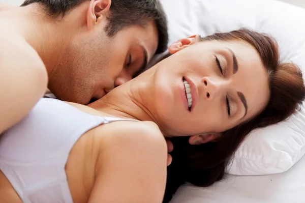 Beautiful young loving couple having sex while lying in bed — Stock Photo, Image