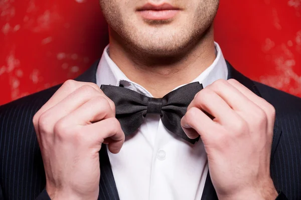 Handsome young man in formalwear adjusting his bow tie — Stock Photo, Image