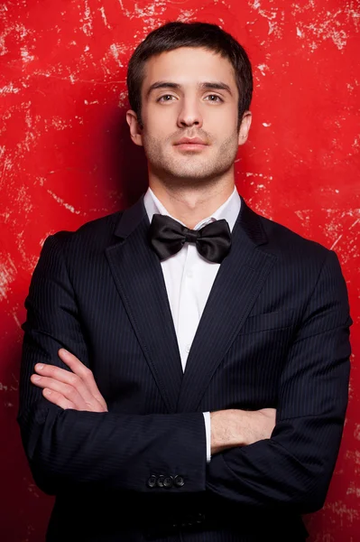 Handsome man in suit and bow tie keeping arms crossed and looking at camera — Stock Photo, Image