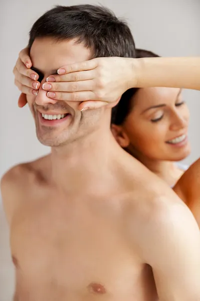 Loving couple standing back to back while woman covering her boyfriend eyes Stock Picture