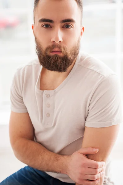 Man in t-shirt and looking at camera while sitting on the chair — Stock Photo, Image