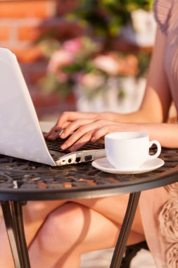 Woman working at laptop while sitting at the outdoor cafe clipart