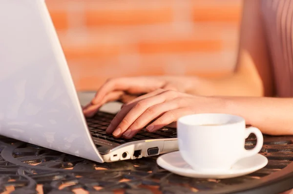Kvinna som arbetar på laptop medan du sitter på uteservering — Stockfoto