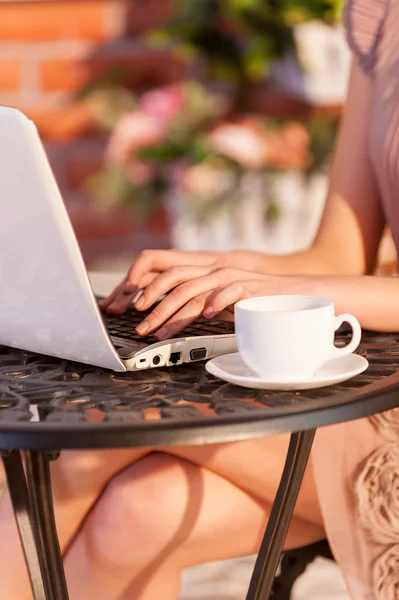 Женщина работает за ноутбуком, сидя в кафе на открытом воздухе — стоковое фото