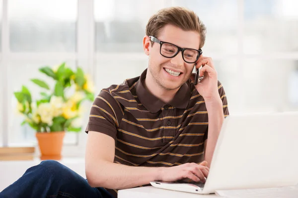 Man in glazen die op laptop werkt en praten over de mobiele telefoon — Stockfoto