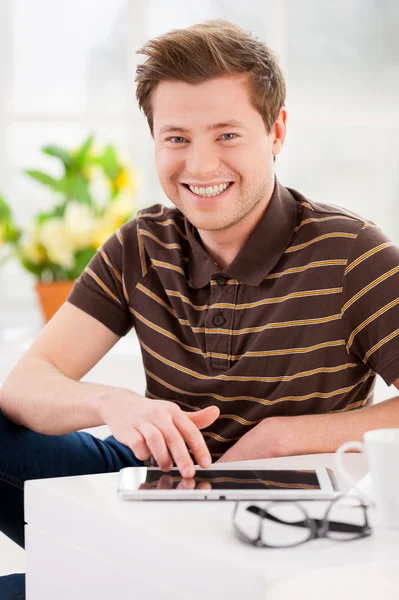 Чоловік працює на цифровому планшеті і посміхається — стокове фото
