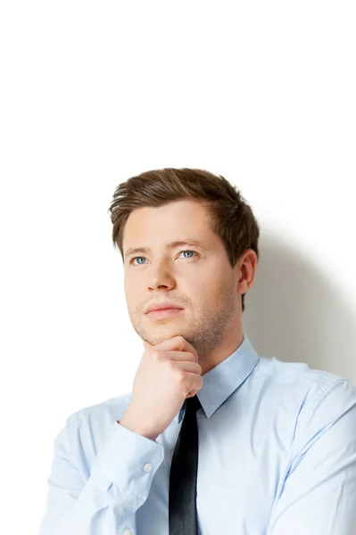 Man in shirt and tie holding hand on chin and looking away — Stock Photo, Image