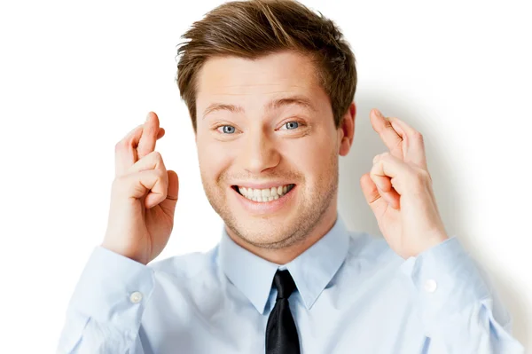 Happy young man in shirt and tie keeping fingers crossed and smiling — Stock Photo, Image