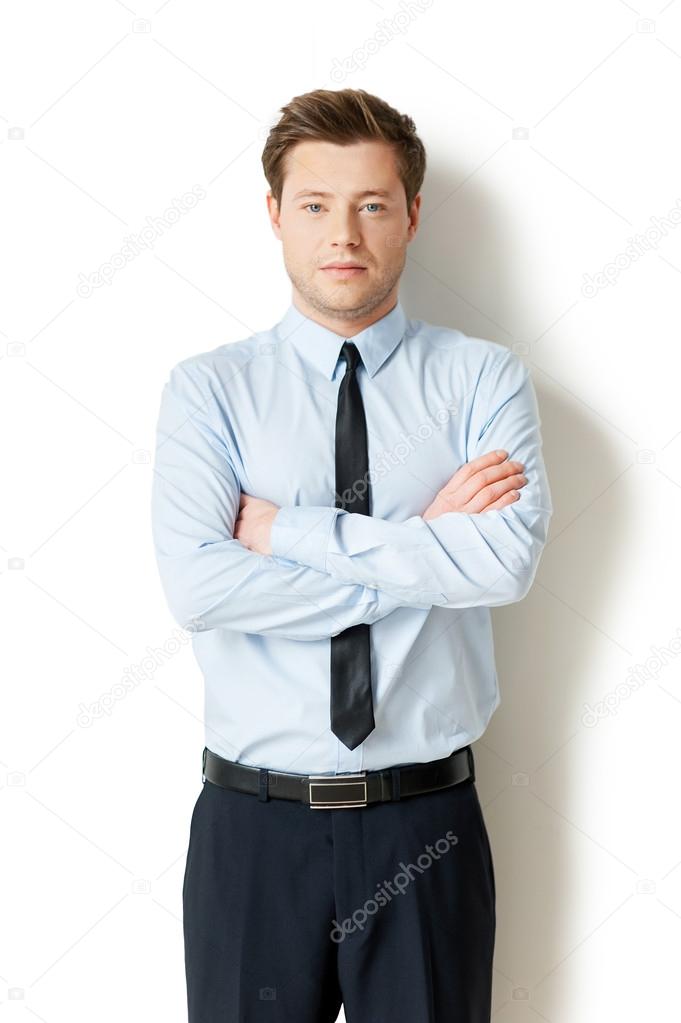 Man in formalwear looking at camera and keeping arms crossed