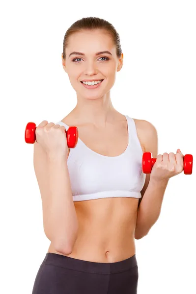 Woman in sports clothing training with dumbbells and smiling — Stock Photo, Image