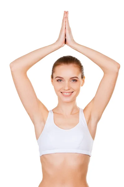 Woman in sports clothing keeping hands clasped upon head and smiling — Stock Photo, Image