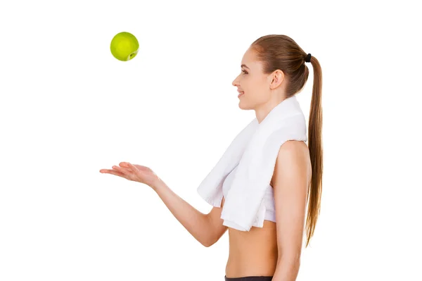 Woman throwing a green apple up and smiling — Stock Photo, Image
