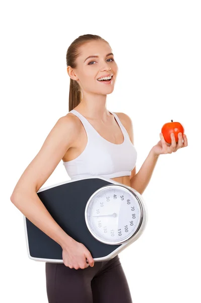 Woman in sports clothing holding weight scales and apple — Stock Photo, Image