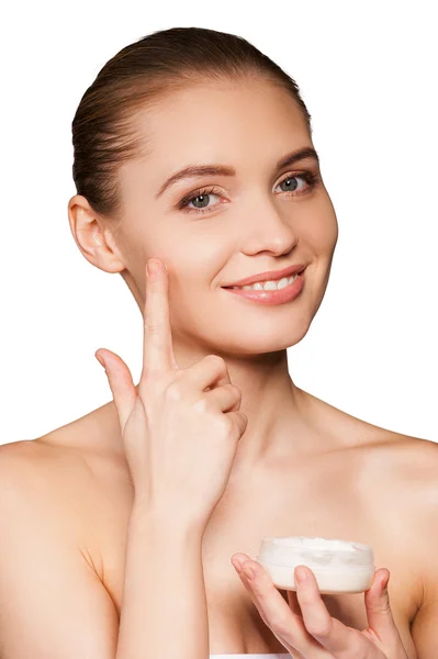 Woman wrapped in towel spreading cream on her face — Stock Photo, Image