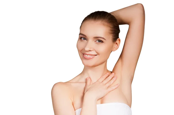 Woman wrapped in towel touching her skin and smiling while standing Stock Photo