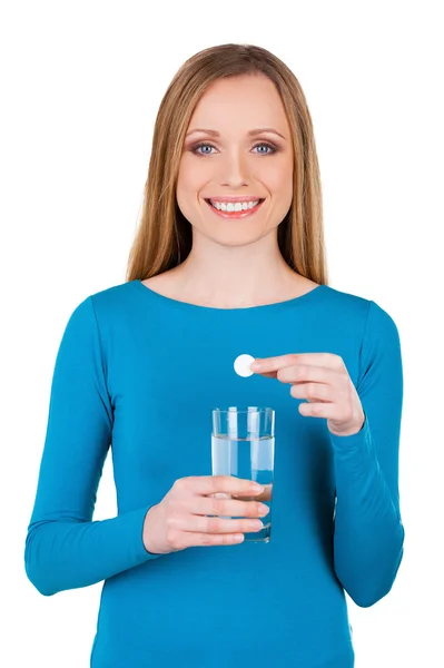 Mujer sosteniendo una píldora sobre vidrio con agua — Foto de Stock