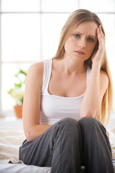 Frustrierte junge Frau hält Kopf in der Hand und drückt Negativität aus — Stockfoto