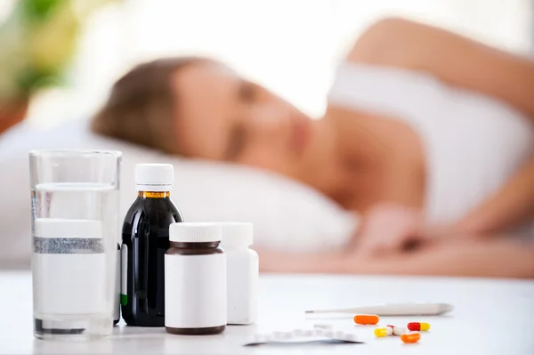 Femme couchée au lit pendant que les médicaments sont au premier plan — Photo