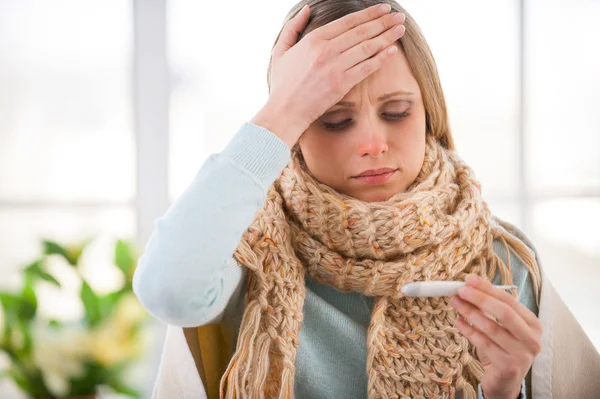 Young woman covered with plaid checking her body temperature — Stock Photo, Image