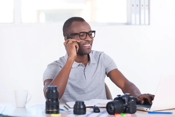 아프리카 남자 그의 작업 장소에 앉아 및 휴대 전화 통화 — 스톡 사진