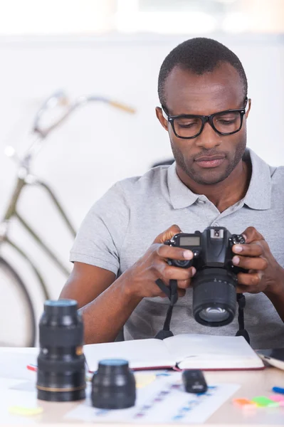 Africano hombre en casual comprobar fotos en su cámara —  Fotos de Stock